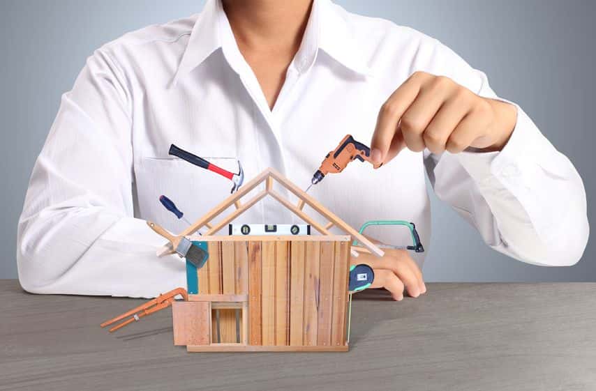 a woman in a white shirt is working on a model house