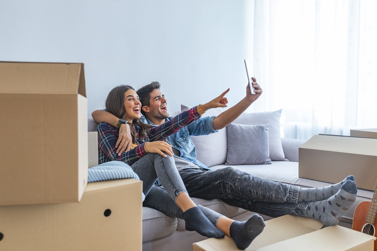 a man and woman are sitting on a couch looking at a tablet