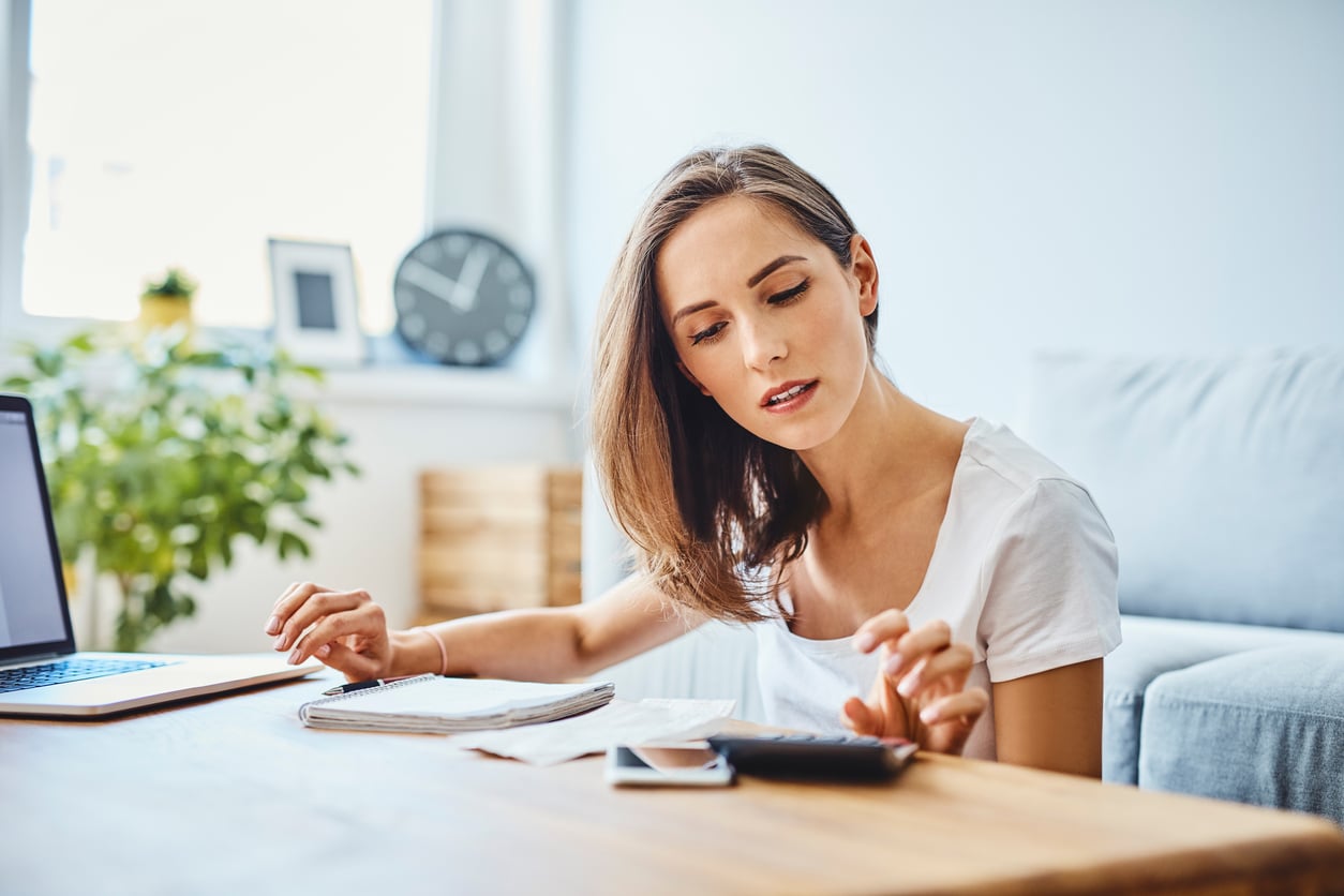 a woman sitting at a desk with a laptop and a calculator