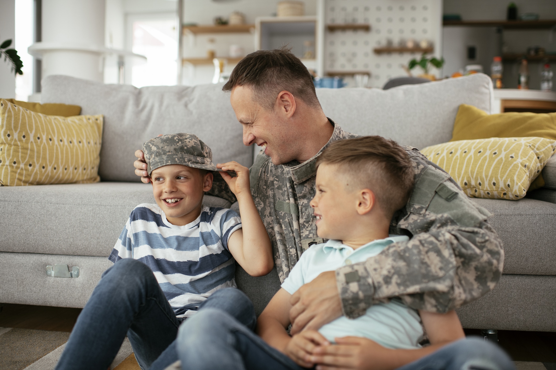 a man in a military uniform sits on the floor with two boys