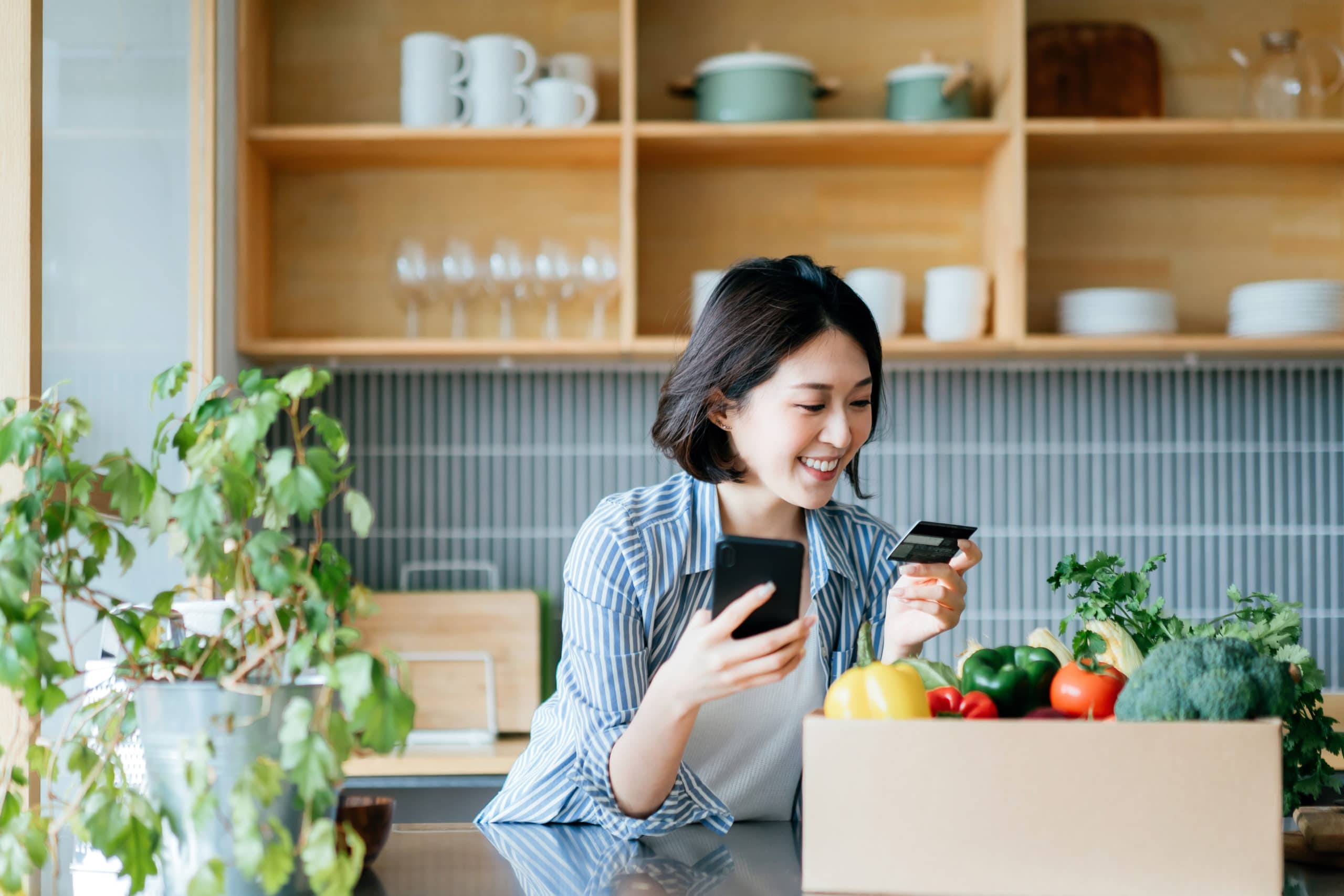 a woman holding a credit card and looking at her phone