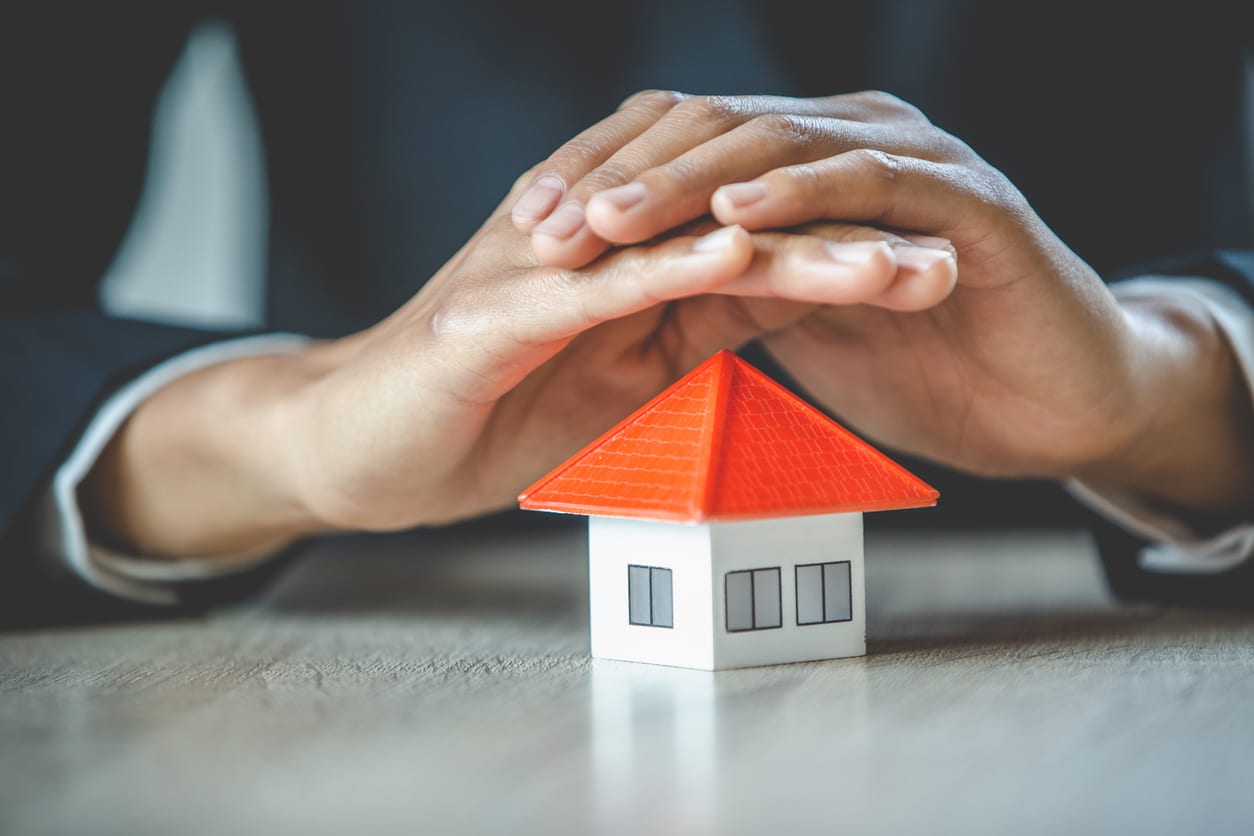 a person covering a small house with their hands