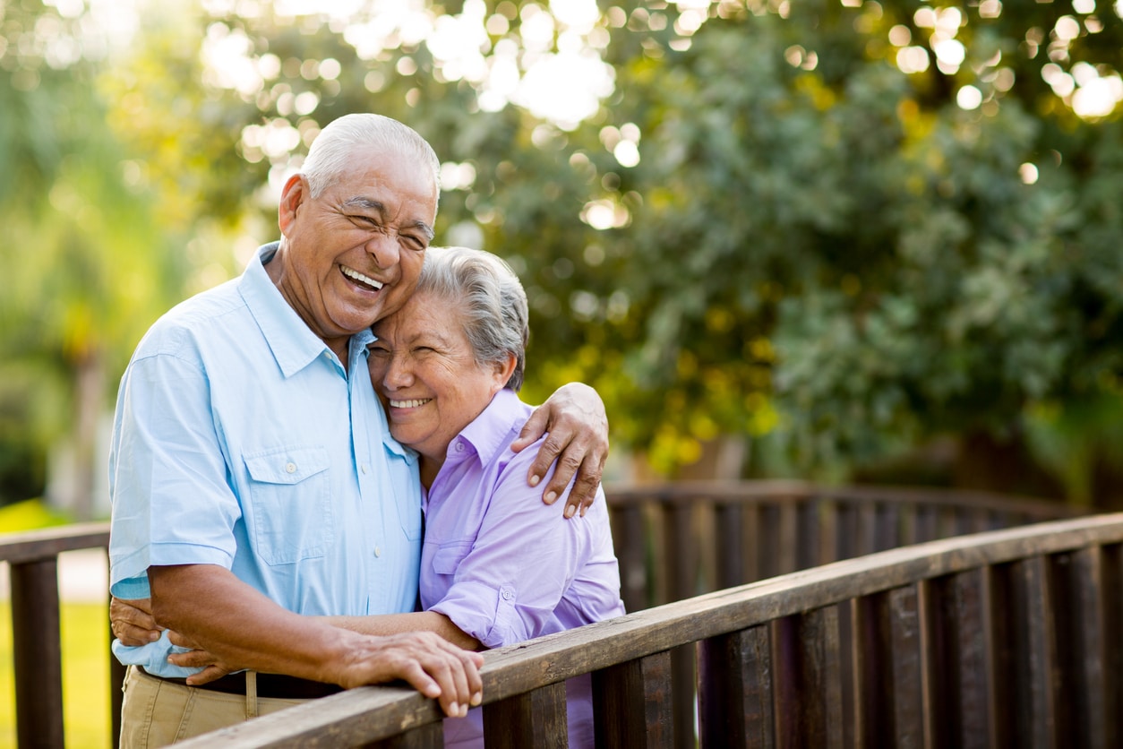 a man and woman are hugging and smiling on a bridge