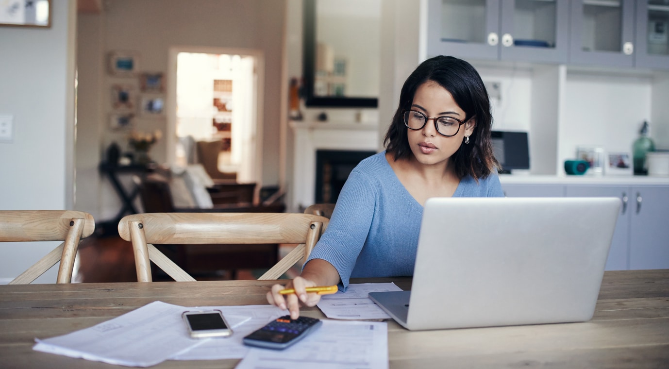 a woman sitting at a table using a laptop and a calculator